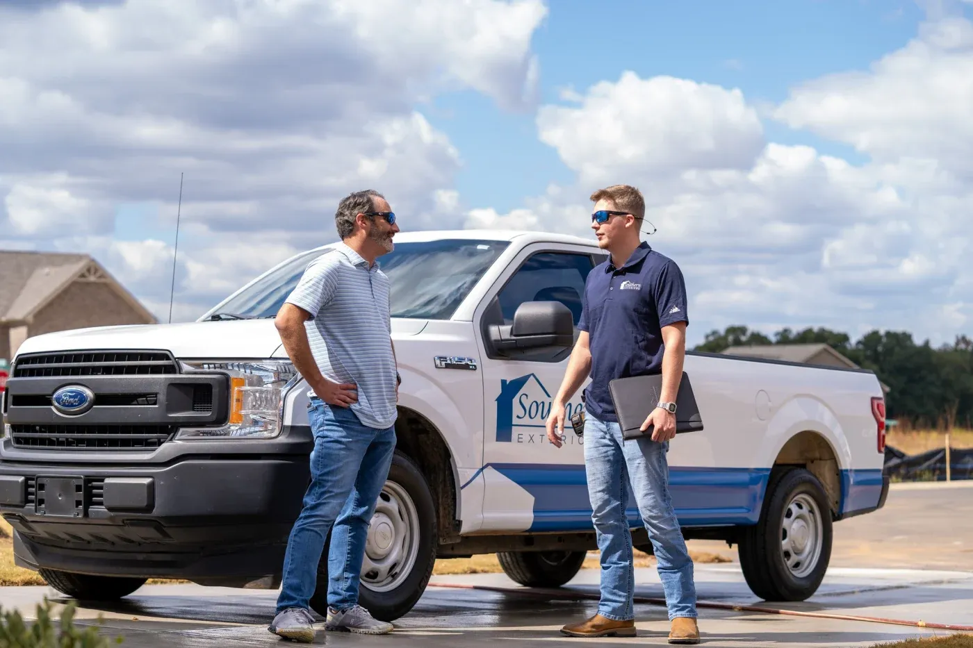 A Southern Exteriors team member talking with a homeowner beside a branded work truck.