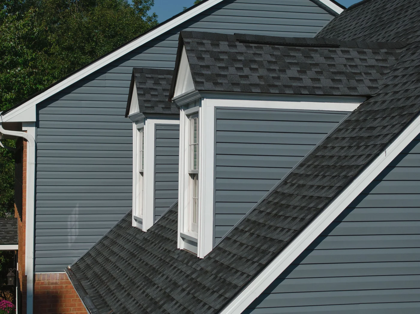 Expert Roofing Services | Columbia, SC | Southern Exteriors A detailed side angle showcases a steep roofline finished with fresh, dark architectural shingles that perfectly frame two white-trimmed dormer windows set against gray horizontal siding.