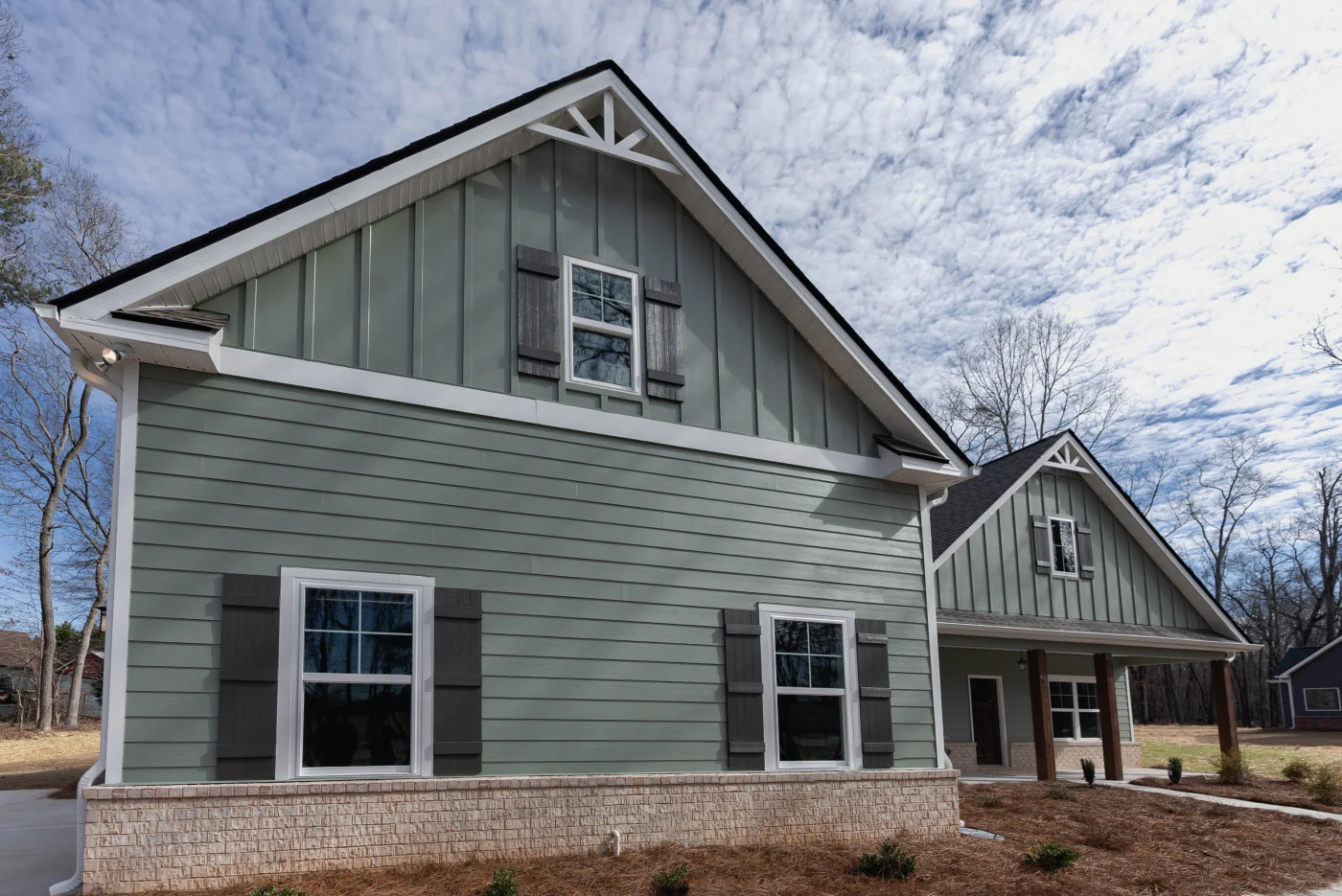 Gorgeous Siding Replacements | Columbia, SC | Southern Exteriors This multi-gabled home features sage green horizontal siding on the lower level nicely paired with matching vertical board and batten panels in the peaks and dark wood shutters.