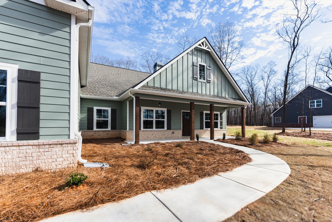 Spectacular Siding Services | Columbia, SC | Southern Exteriors A curving concrete walkway leads toward a beautiful ranch-style home featuring sage green horizontal lap siding perfectly balanced by vertical board and batten panels on the gabled peak.